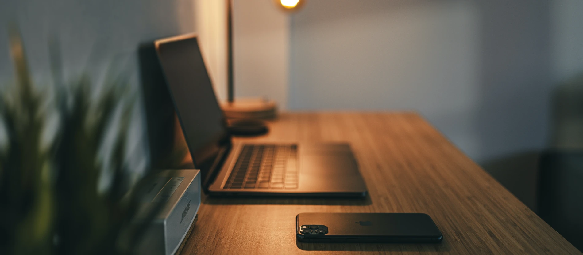 A wooden desk with a MacBook and some desk accessories. No person is in the photo.